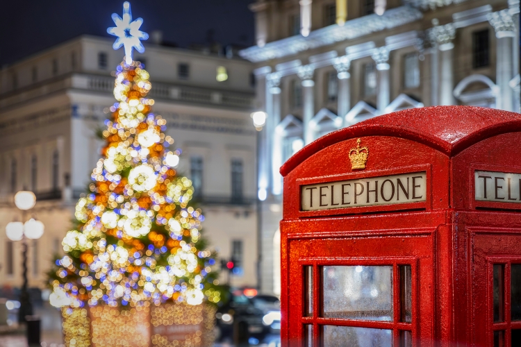 Rote Telefonzelle vor beleuchtetem Weihnachtsbaum in London zur Weihnachtszeit